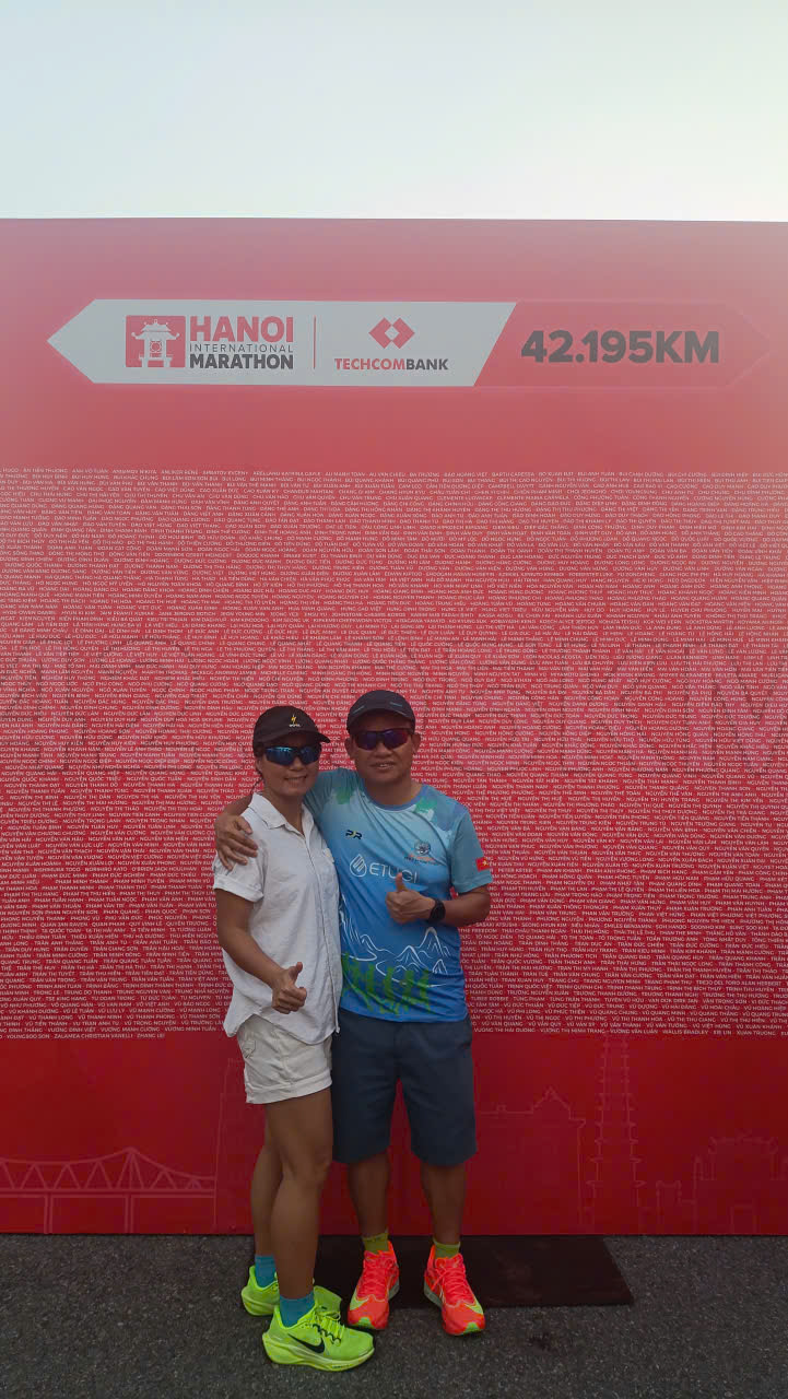 Lịch tập chạy bộ 8 tuần — vợ chồng tác giả trước backdrop 42.195KM